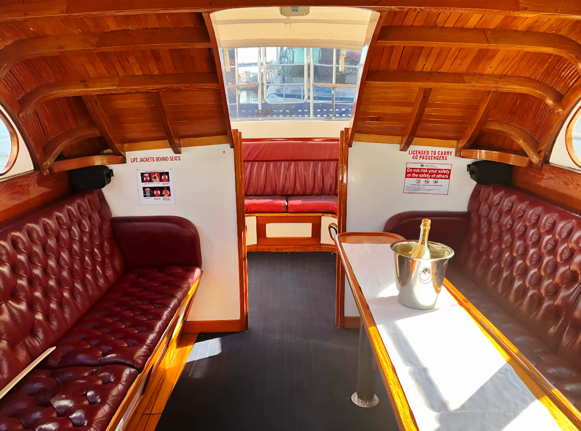 The saloon of Elizabeth Anne — buttoned oxblood chesterfields beneath a varnished timber ceiling